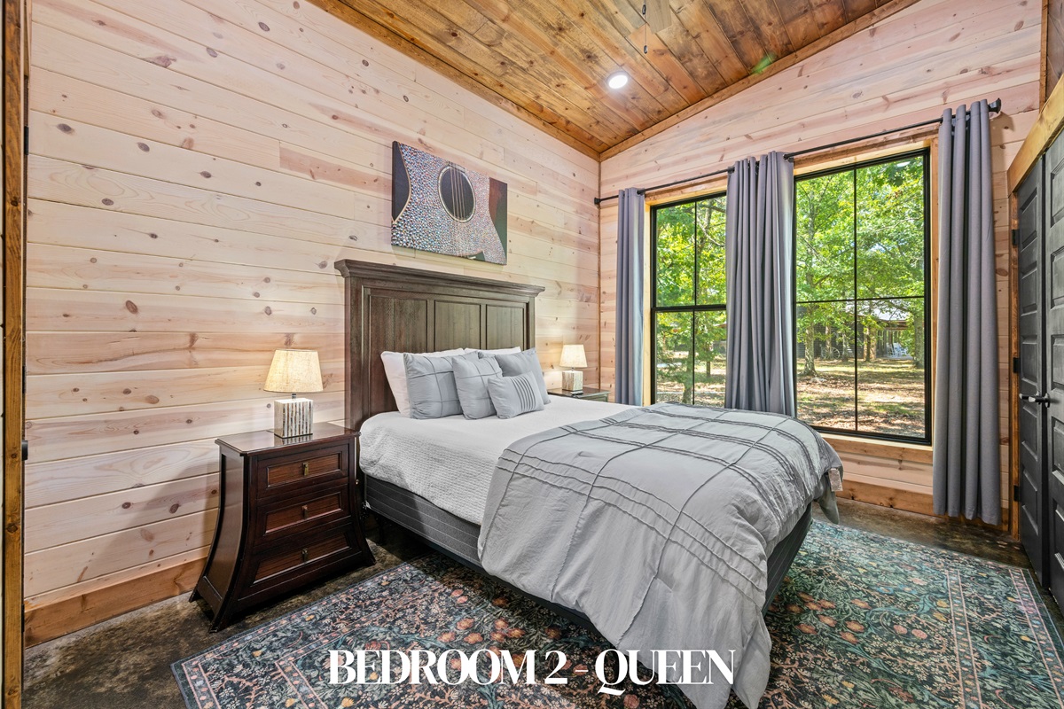 Bedroom 2: Queen bed with warm accents and natural light.