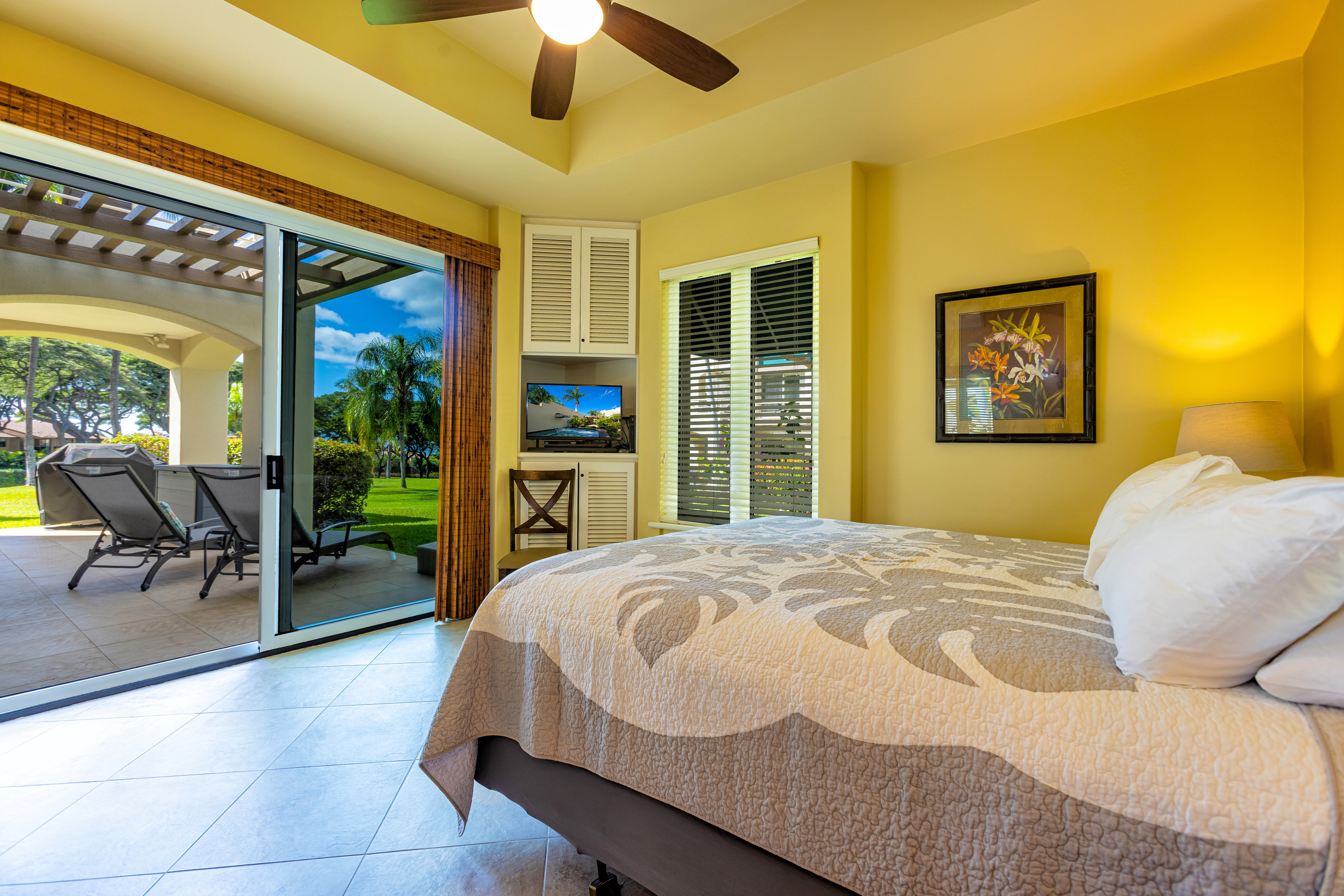 The main bedroom has a sliding door onto the large wrap-around lanai (two chaise-lounges just outside)