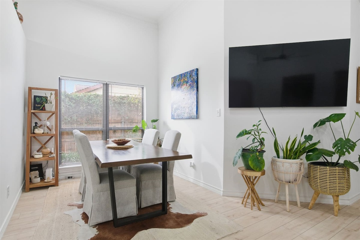 Bright dining space with table seating for four, modern lighting, and open flow into kitchen and living areas for comfortable shared meals and easy TV watching.
