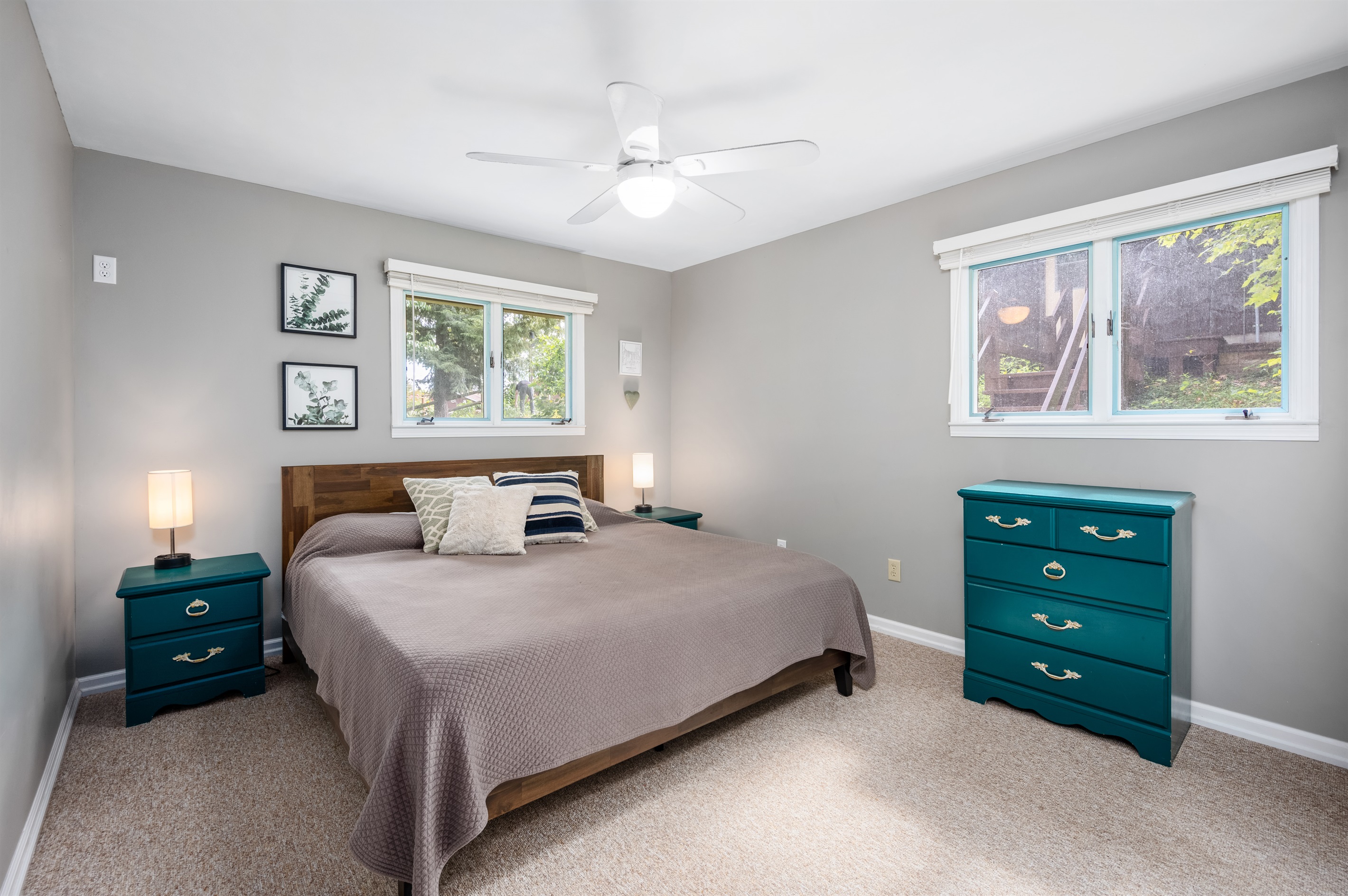 Main level bedroom with queen bed, dresser, and wooded views