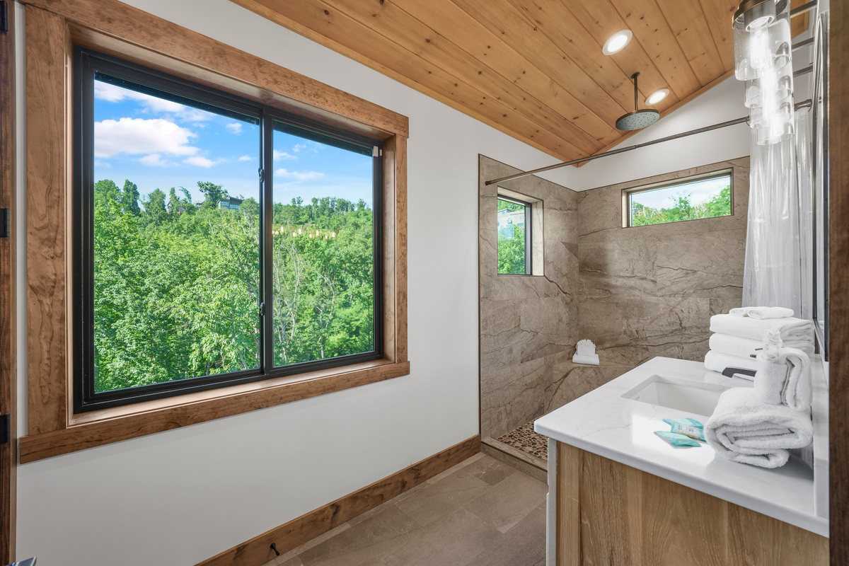 King Suite with vaulted ceilings an x-large TV. Unwind in the en-suite bathroom featuring a luxurious walk-in shower with a natural river rock floor, bringing  the Smoky Mountains indoors for a spa retreat.