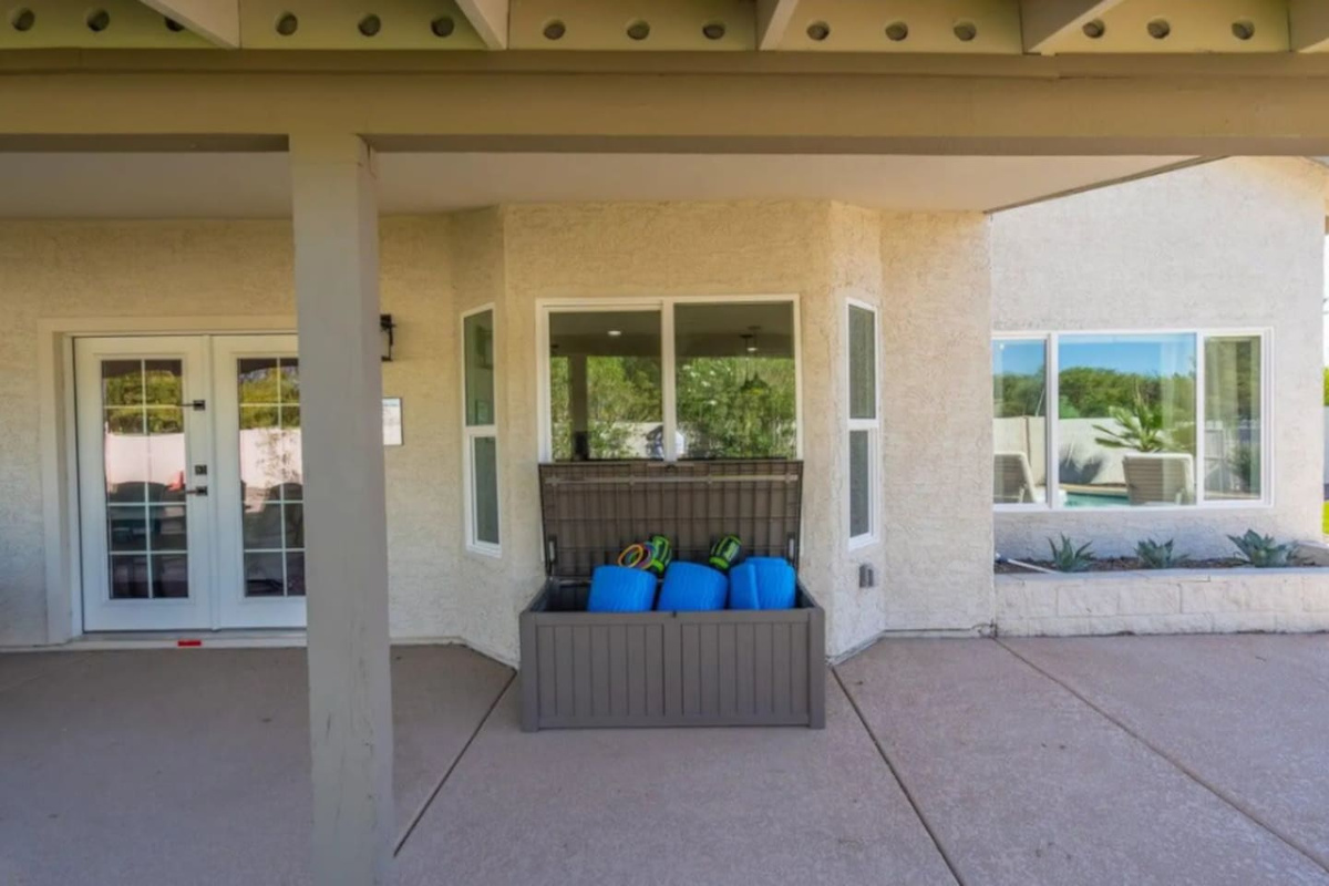 Covered patio with easy pool access, storage, and multiple glass doors opening to resort-style backyard.
