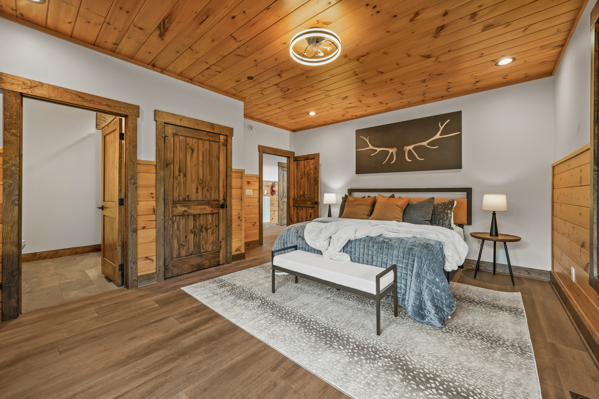 Relax in the spacious king bedroom with a large TV, dedicated desk workspace & direct deck access. Unwind in the en-suite bathroom featuring a walk-in shower with a natural river rock floor, bringing  the Smoky Mountains indoors for a spa retreat.