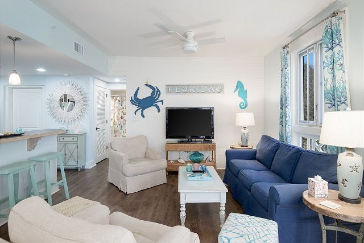 Living room with HDTV, blue sleeper sofa and armchairs, open to the kitchen breakfast bar