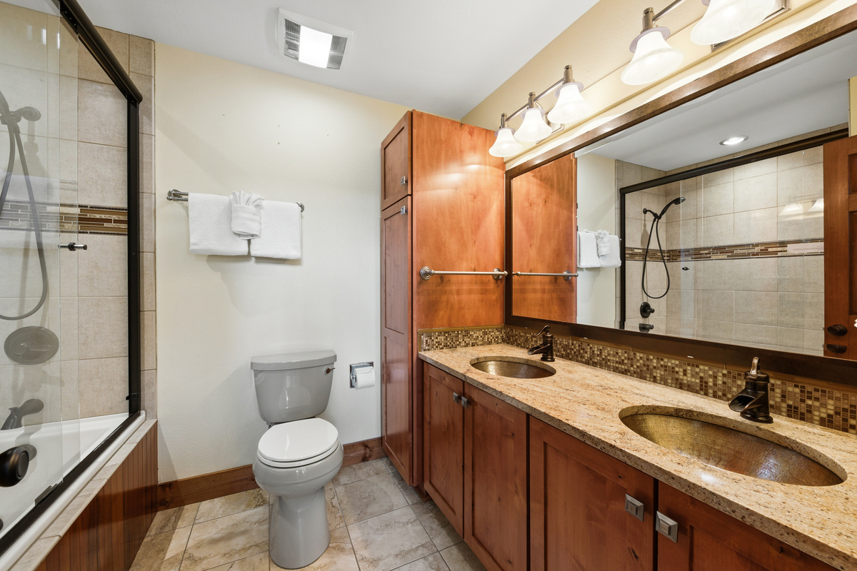 Primary full bathroom with dual-vanity sinks and combination shower/tub. 