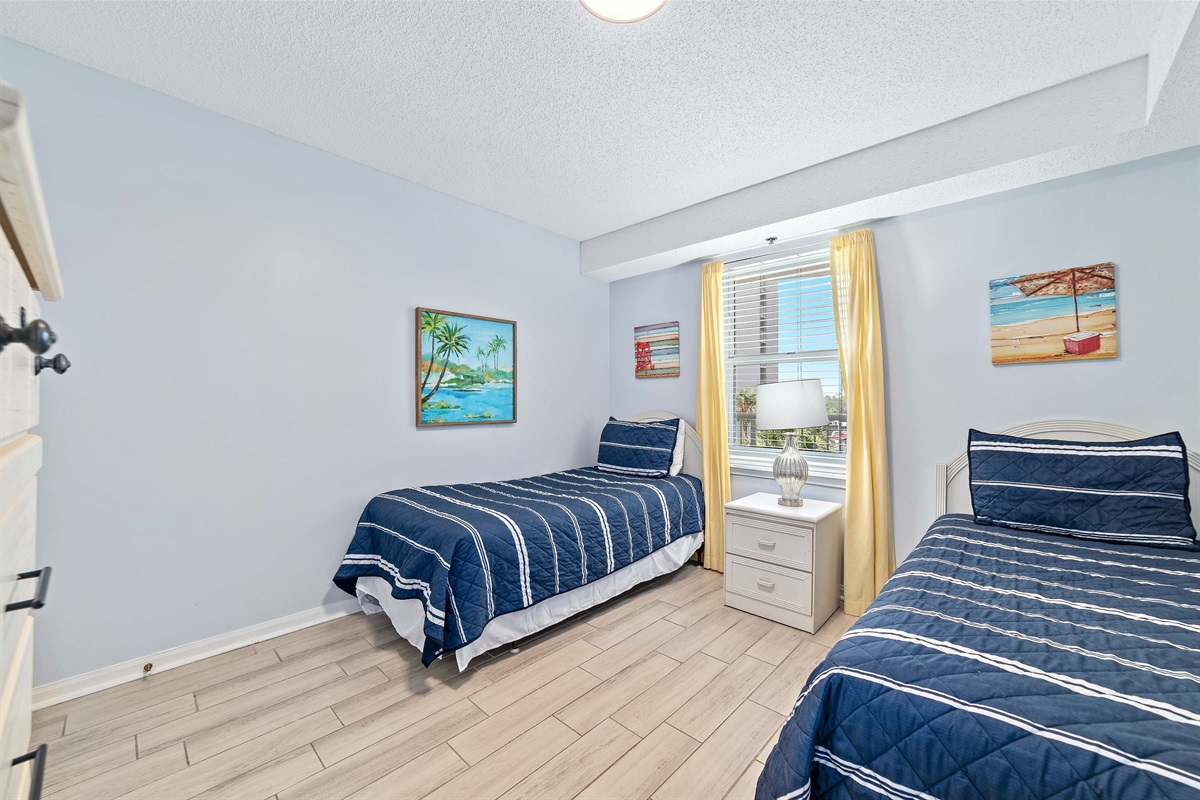 Twin Room -Coastal-inspired bedroom with two twin beds, featuring light and airy decor and a glimpse of the surrounding scenery.