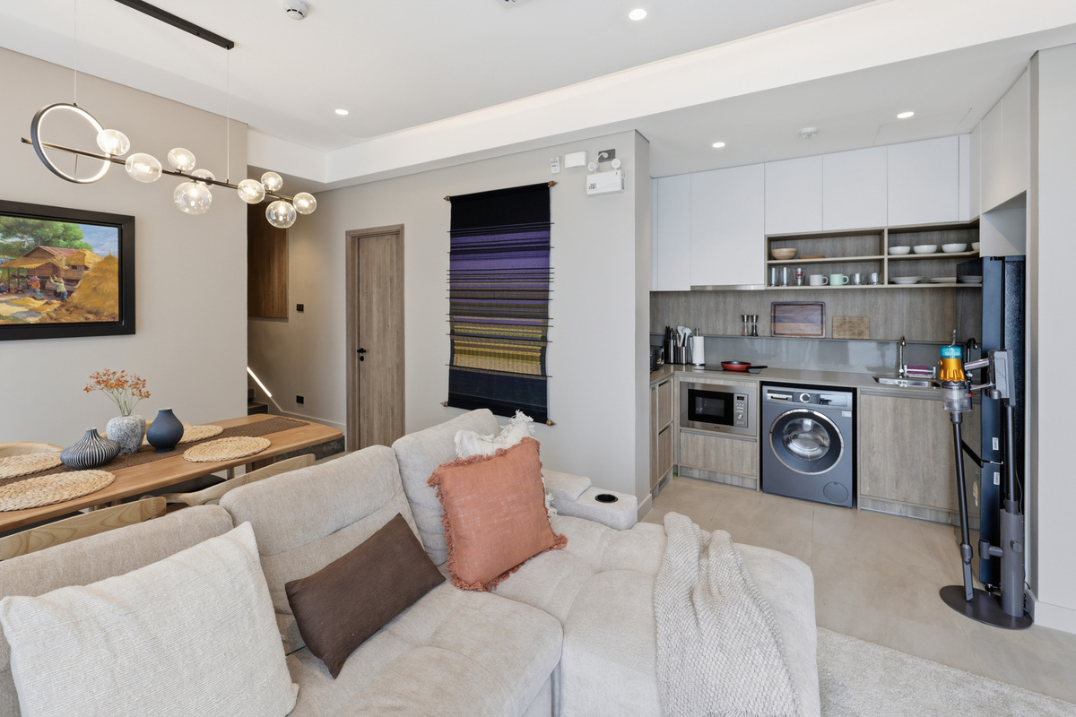 Studio with cream sofa, open kitchen, washer-dryer, and dining area in neutral modern design.