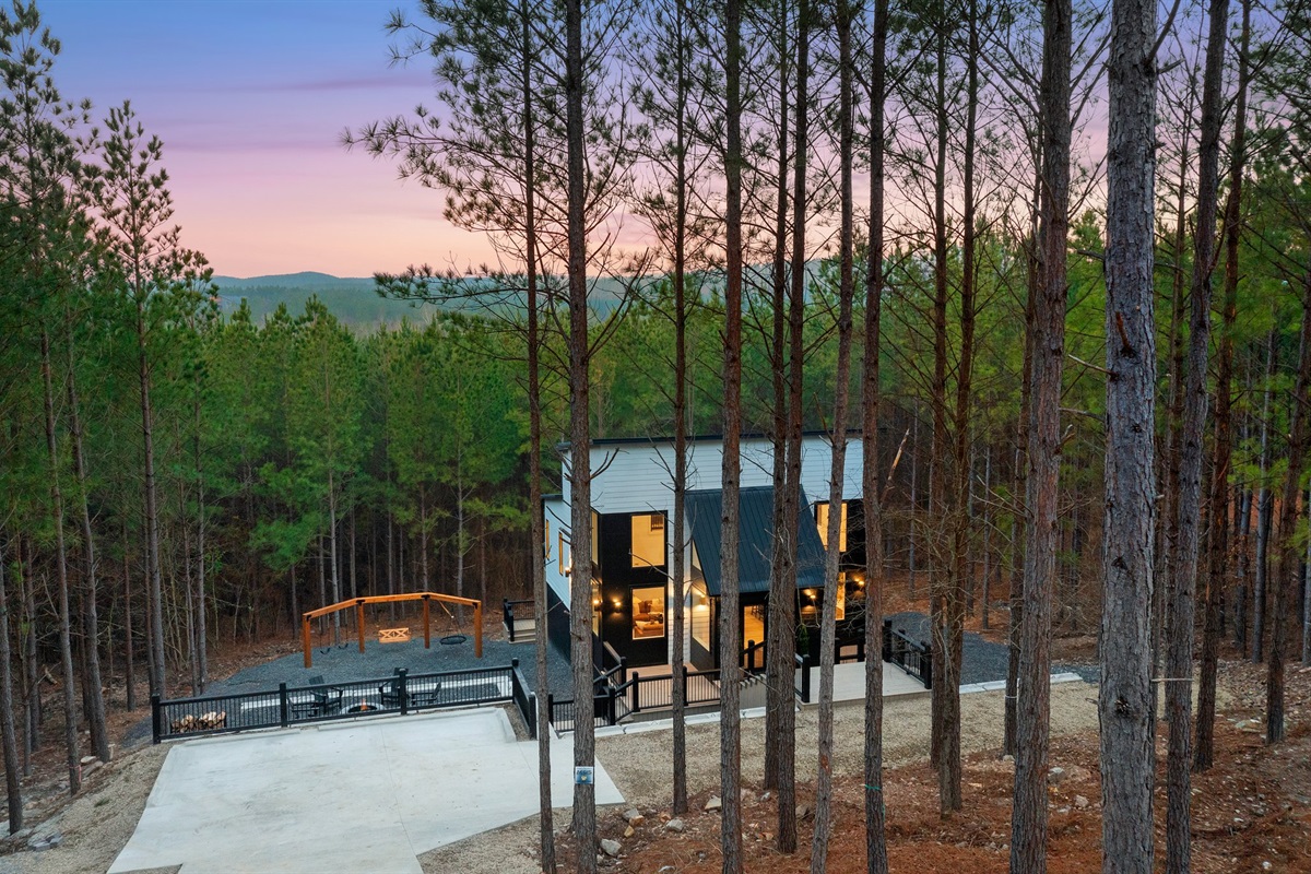 Floor-to-ceiling windows glow warmly at sunset, welcoming you home.