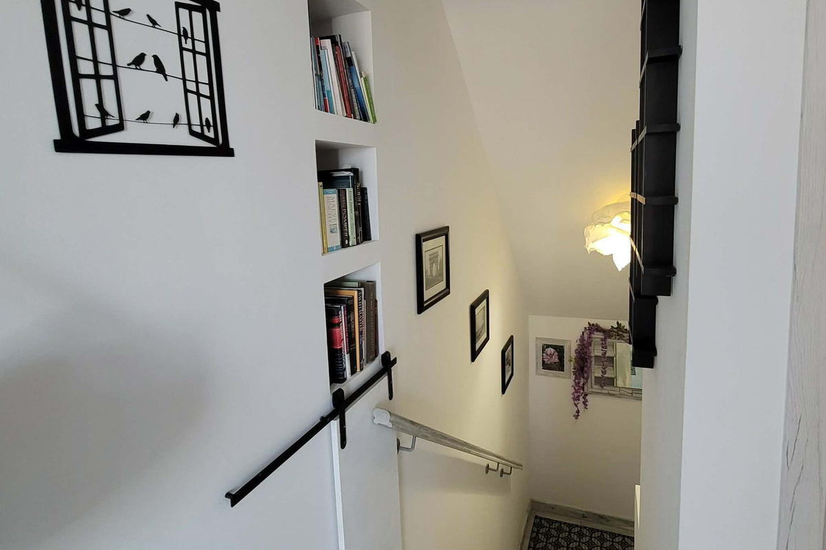 Book case and stairs that lead to the common area with assorted reading material including Greek language and tour books; a hidden compartment for the vacuum cleaner