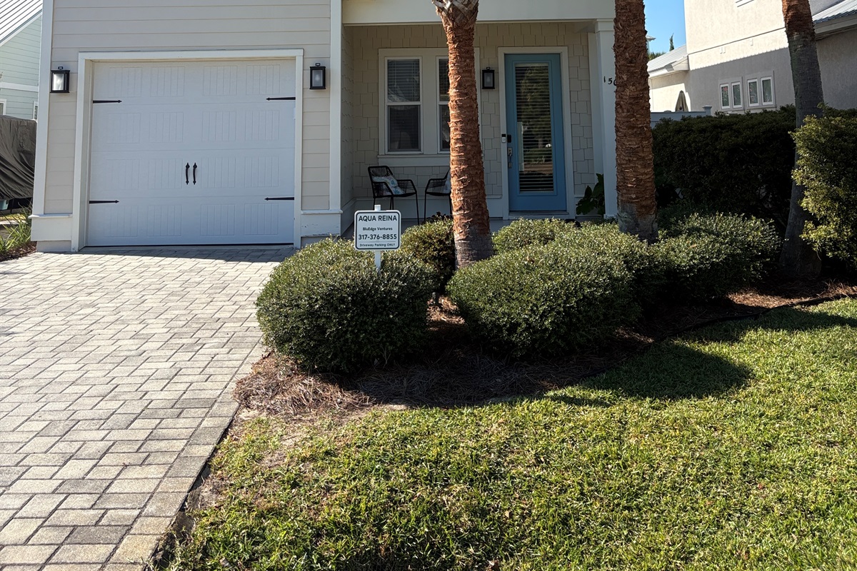 Front entry and driveway with landscaped yard.