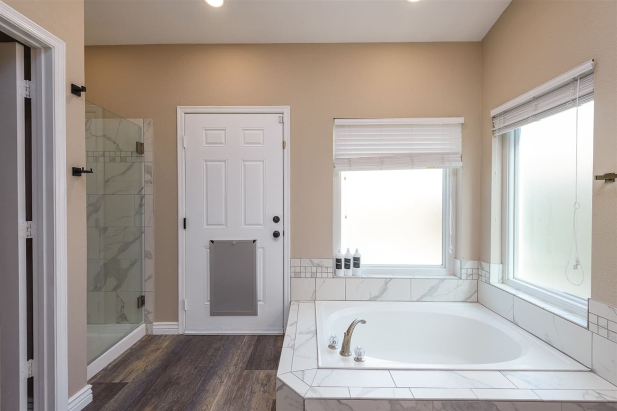 Primary ensuite vanity with double sinks, granite counter space, bright mirror lighting, and direct access from the bedroom.