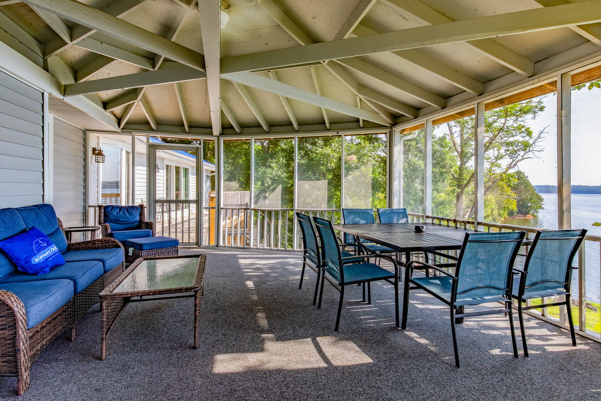 The screened porch offers cushioned seating, dining space, shade, and beautiful Kentucky Lake views.