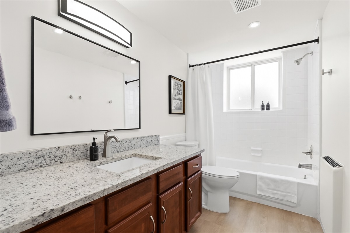Freshen up in a sparkling clean bathroom featuring a deep soaking tub, rain shower head, soft white towels, and stylish wall art.