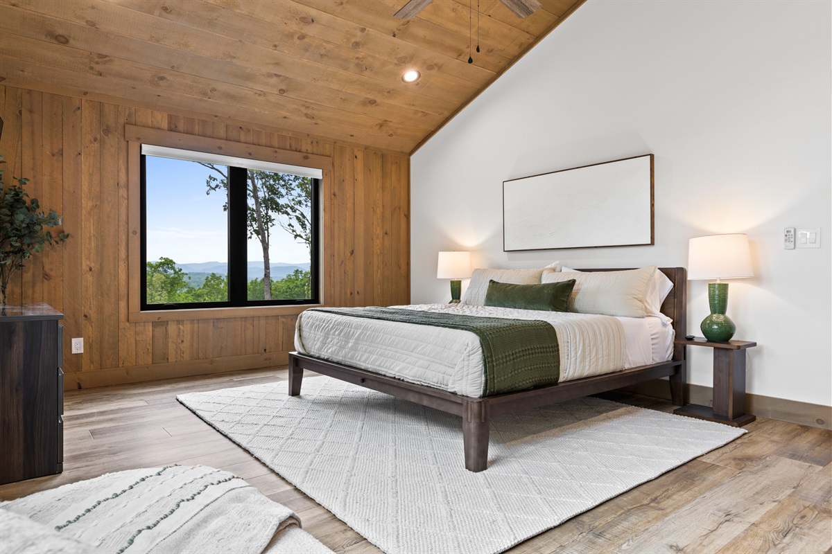 Spacious primary bedroom with vaulted wood ceilings, serene mountain views, and a cozy, modern design.