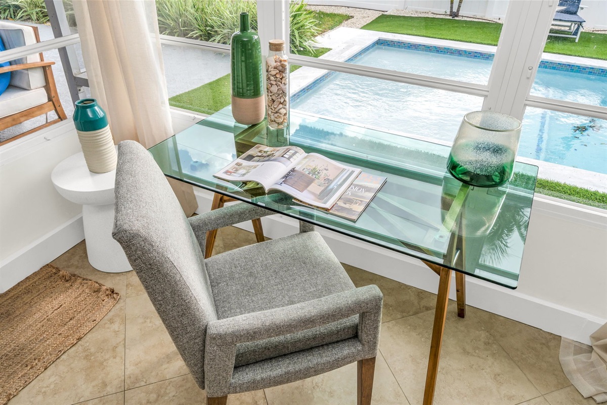 A beautifully designed Florida sunroom with wrap-around windows, modern furnishings, a Smart Fire streaming TV, and tranquil pool views—ideal for lounging, morning coffee, or working in style.