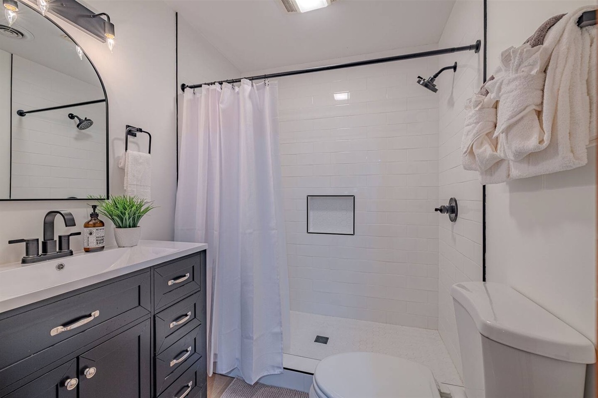 With its airy white tile shower and updated vanity, this shared upstairs bathroom delivers a fresh, spa-inspired feel.