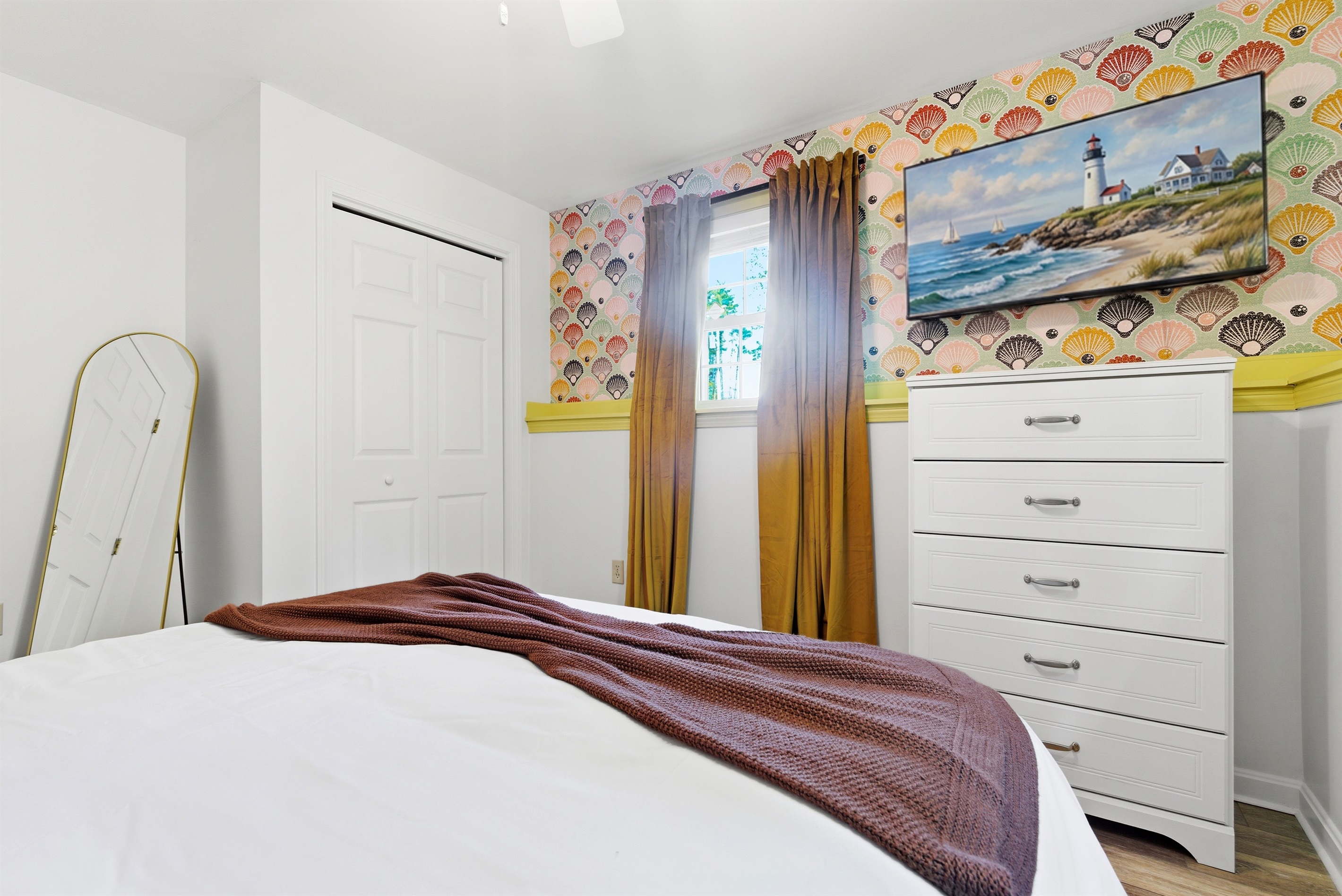 A comfortable bedroom featuring a twin trundle bed, complemented by a TV, dresser, and a bright window that fills the space with natural light, creating a cozy and functional retreat.