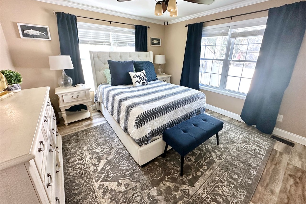 Retreat to this serene bedroom featuring a comfortable tufted bed and soft coastal accents. With dual windows providing plenty of natural light and ample storage in the large dresser, it’s a restful space designed for a great night's sleep.
