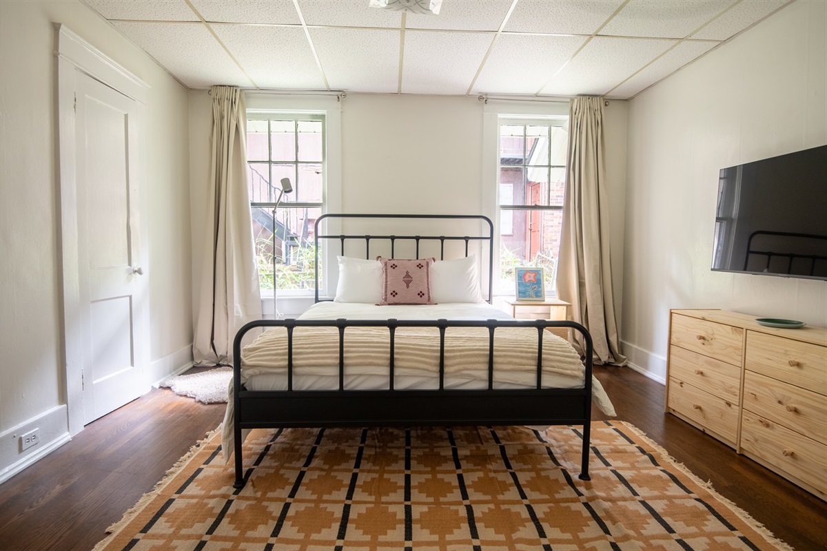 Spacious, light-filled bedroom with queen bed and smart TV for relaxation and comfort.