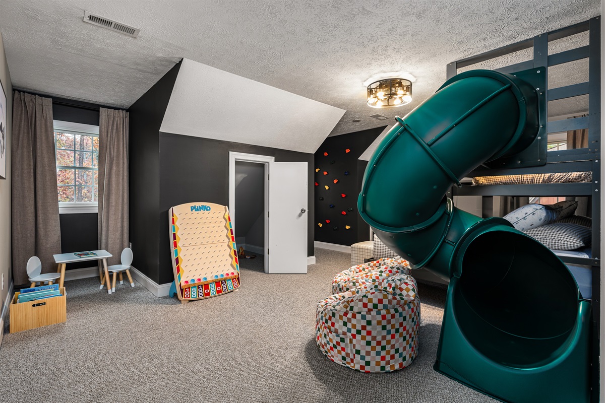 Kids will never want to leave this adventure-themed bunk room with double bunks, a tube slide, rock wall, and play table.