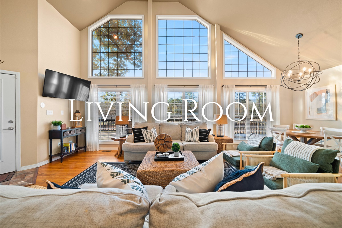 Floor-to-ceiling windows fill the living room with natural light, creating a bright and welcoming gathering space.