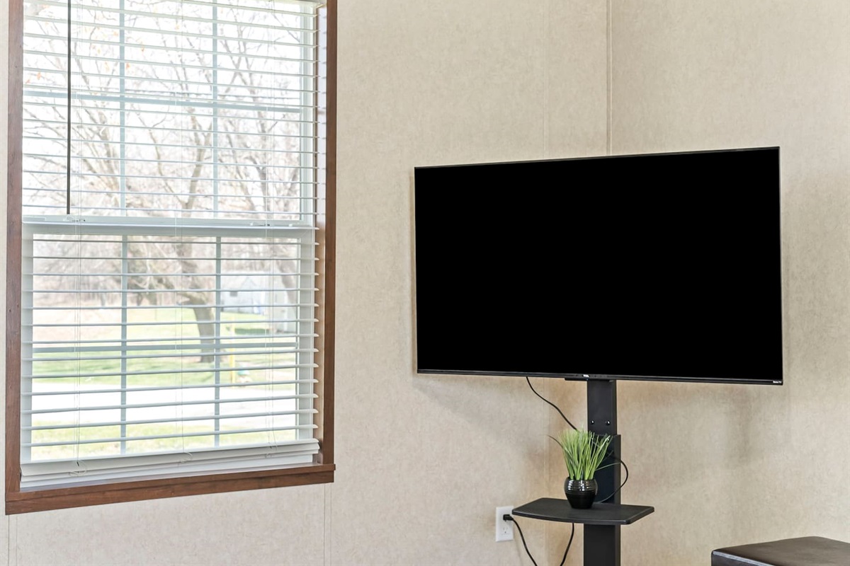 Smart TV setup next to a large window, offering natural light and a perfect spot to relax and stream your favorite shows.