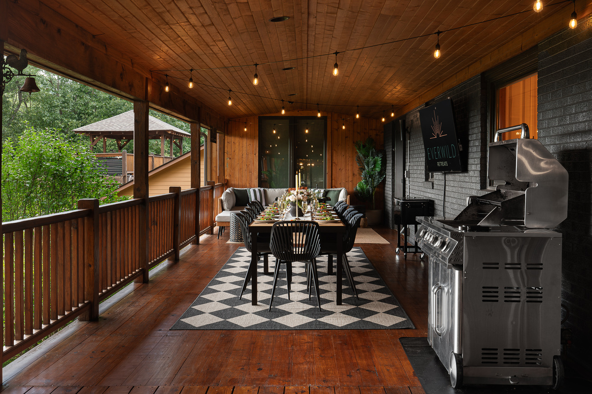 {Covered Dining Deck} Dine outdoors rain or shine with a long group table, grill, beverage cooler, and forest views on the expansive covered deck.