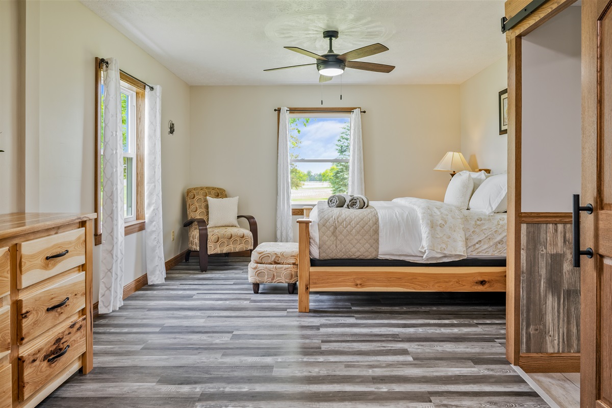 Unwind in this serene bedroom with a plush bed, cozy reading nook, and peaceful window views—perfect for a restful night.