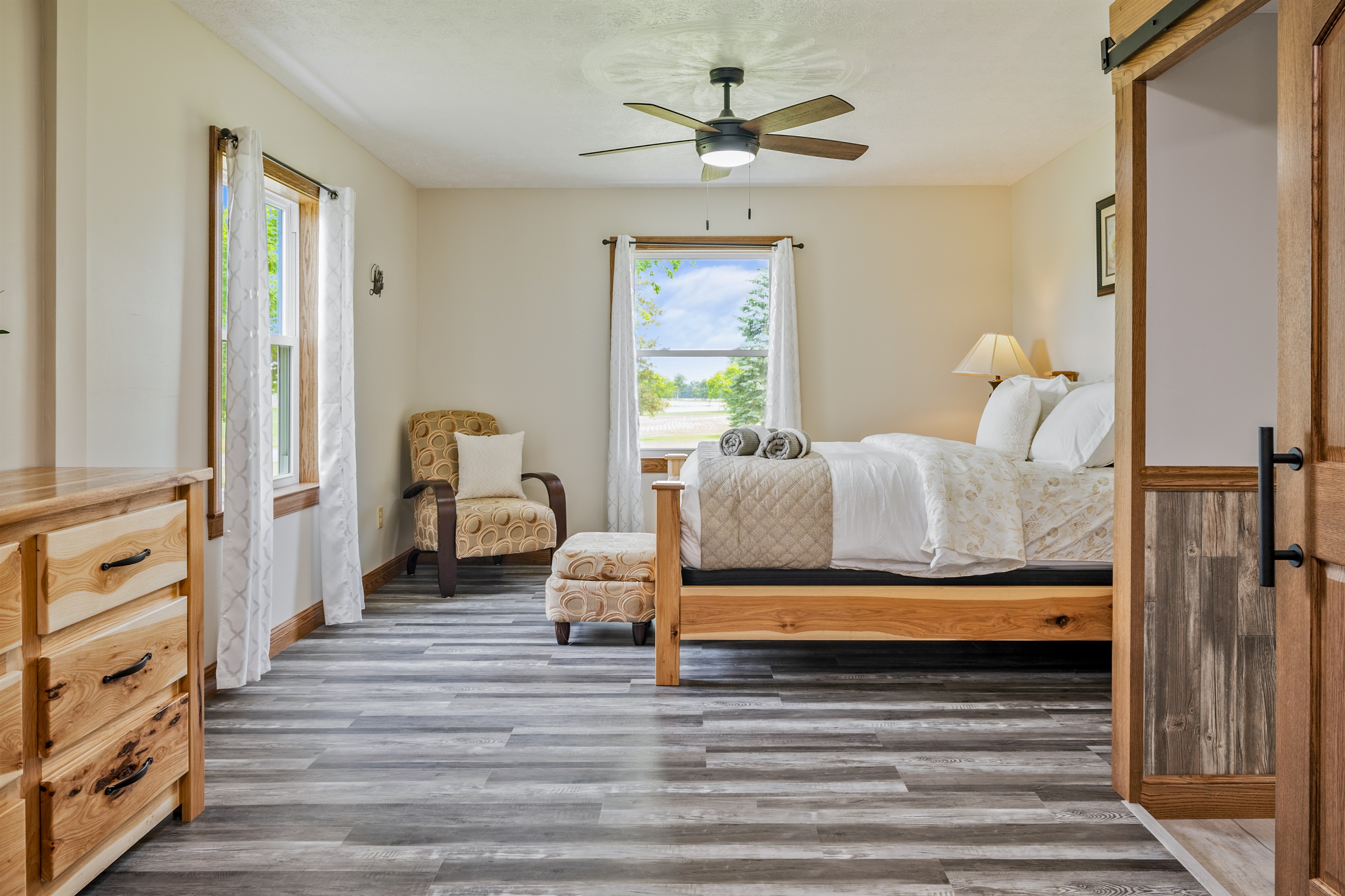 Unwind in this serene bedroom with a plush bed, cozy reading nook, and peaceful window views—perfect for a restful night.