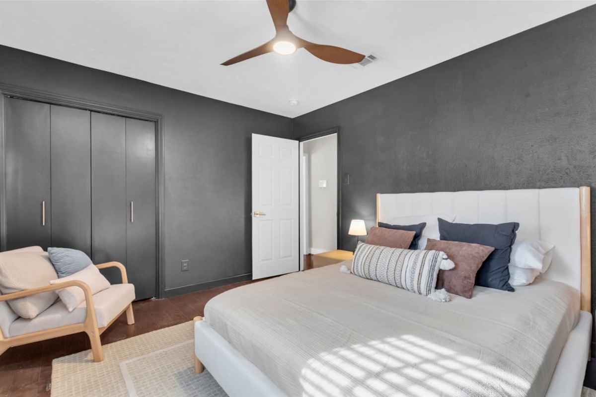 Guest bedroom featuring a queen bed, closet storage, and a comfortable sitting area, creating a relaxing and well-appointed space for your stay.