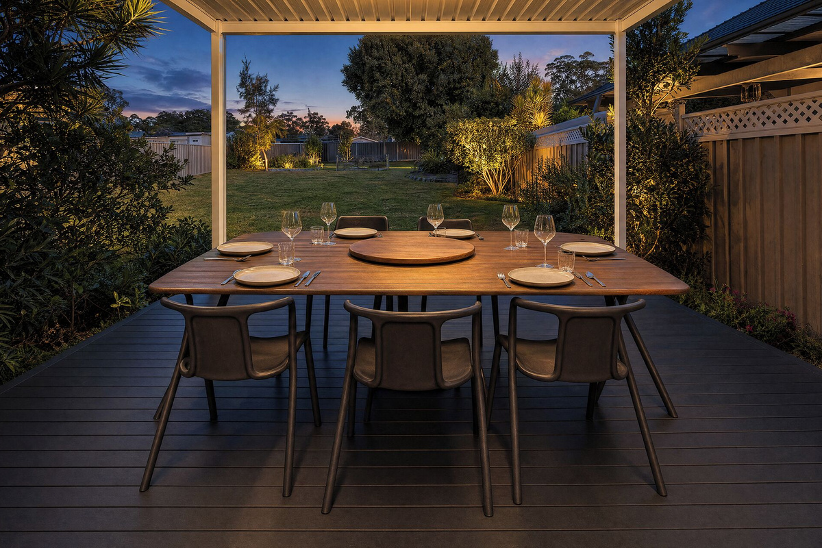 Settle in under the covered deck at Luna’s Sanctuary, with soft garden lighting, open lawn views and an easy evening atmosphere.
