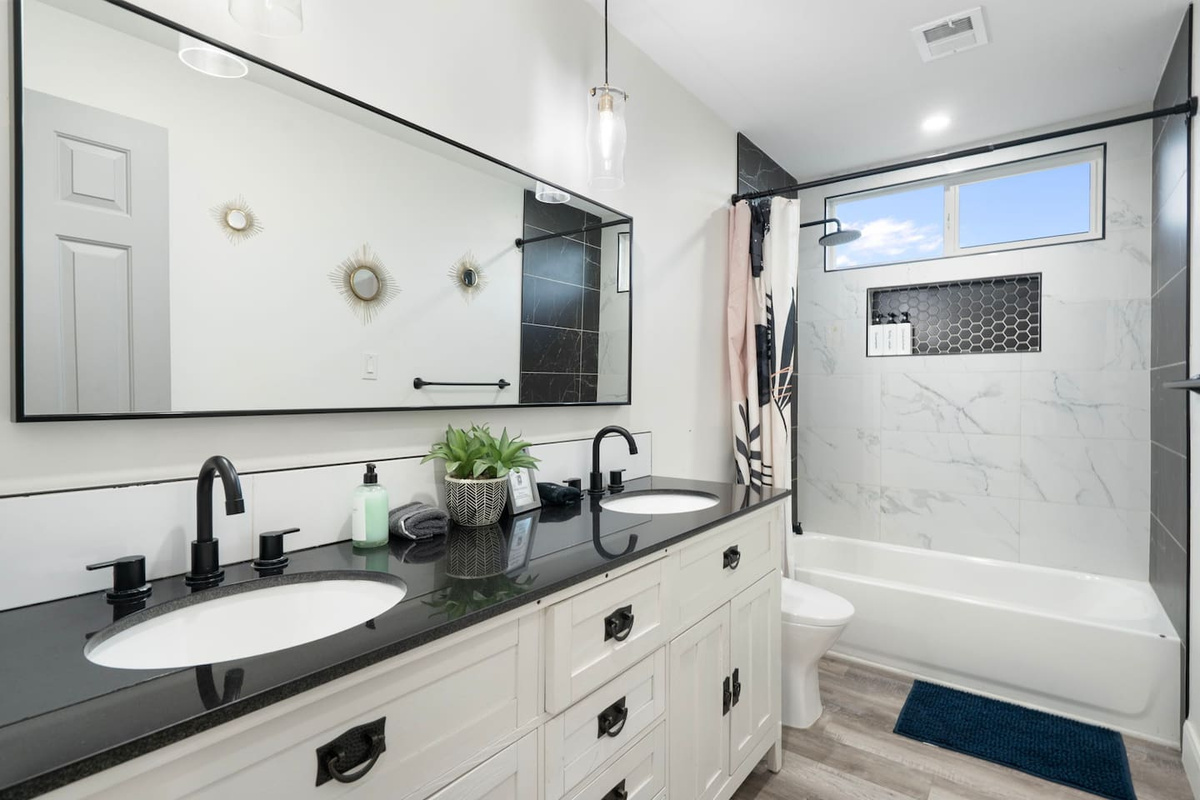 Spa-like primary bathroom with dual vanity, walk-in shower, and modern black and white finishes.
