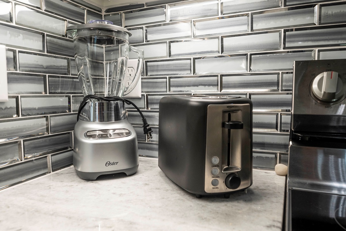 Sleek kitchen corner with modern toaster, blender, and glossy tile backsplash.