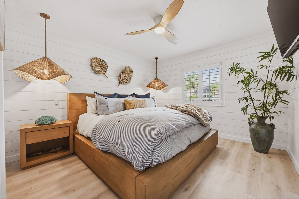 Coastal luxury king suite at El Secreto Azul — hand-crafted wood platform bed, rattan pendant lighting, shiplap walls, and plush bedding designed for the deepest sleep after a perfect day on Destin Beach.