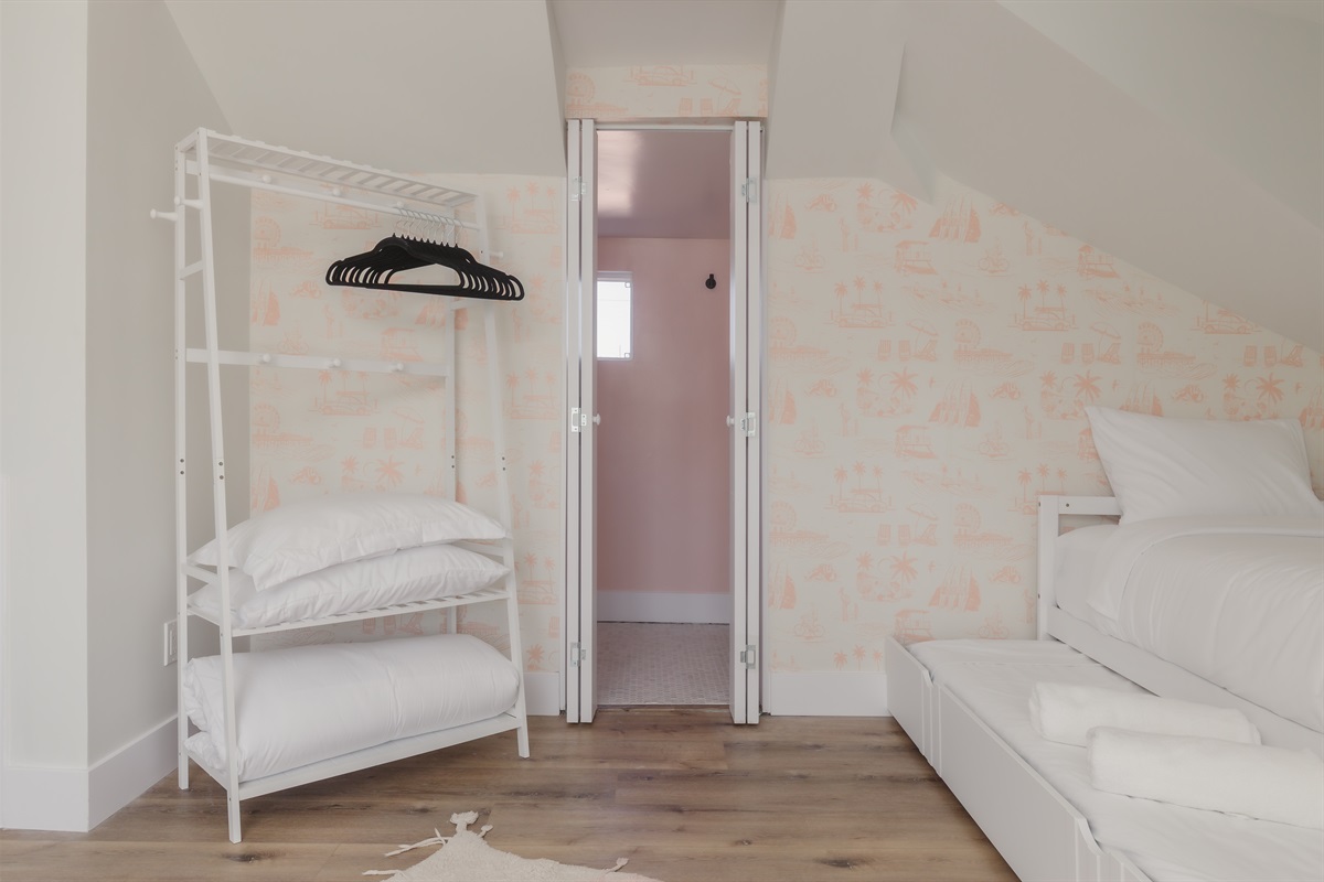 Up and away to our dreamy hideaway ✨🛏️ This sweet upstairs nook features a trundle bed perfect for siblings, cousins, or grown-up crashers after movie night. Tucked under sloped ceilings and splashed with whimsical pink wallpaper, we love this quirky home