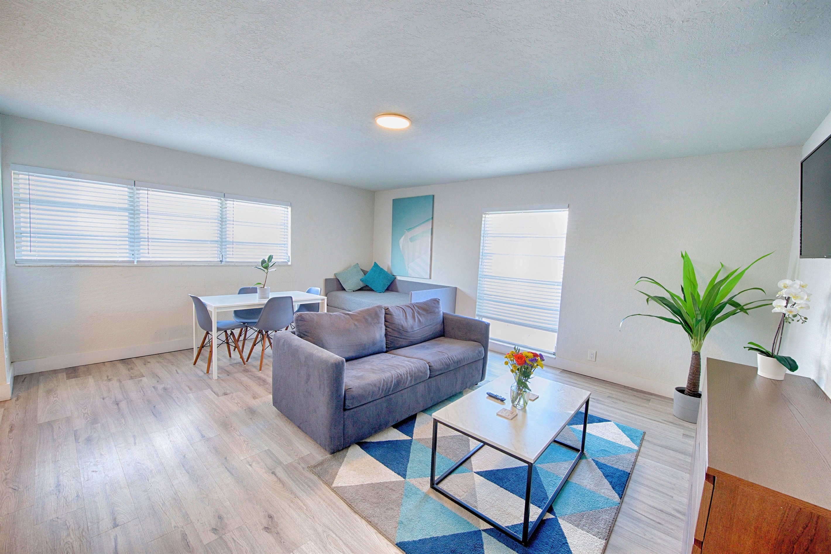 Floor to ceiling windows with sofa, dining table and day bed in the corner
