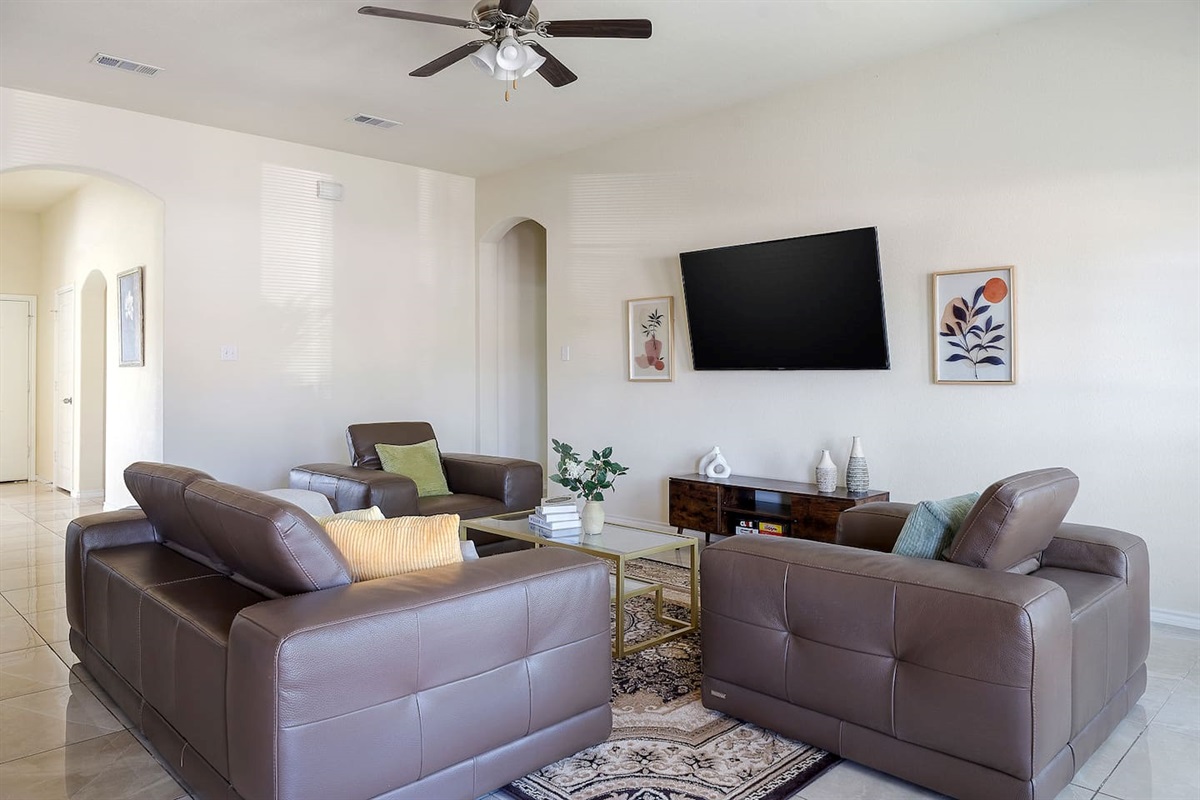 Experience the comfort of this elegant living room, featuring plush leather sofas and a large wall-mounted TV.