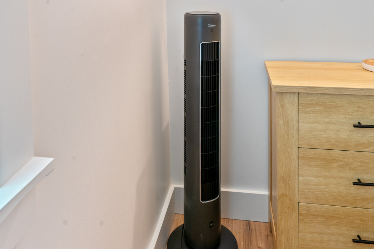 Personalize your room temperature with the sleek oscillating tower fan provided in the bedroom corner. This dedicated cooling unit ensures continuous, quiet airflow to keep you perfectly comfortable throughout warm summer nights.