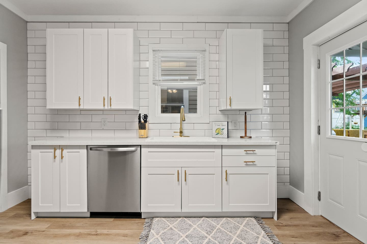 Clean white kitchen with subway tile and stainless dishwasher
