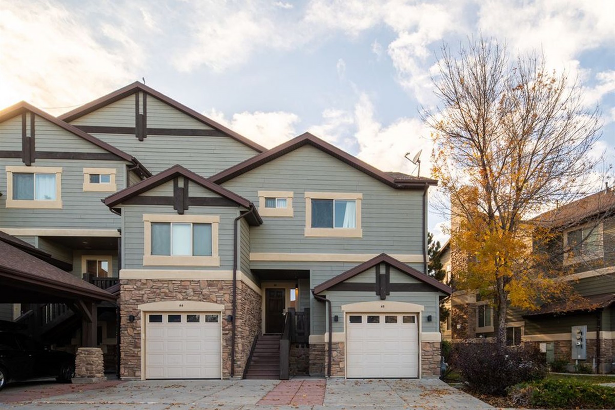Charming townhome exterior with garage parking in a scenic mountain setting.