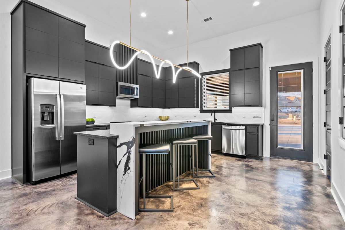 This sleek, modern kitchen combines minimalist cabinetry, bold gold lighting, and a spacious island, creating a chic and functional workspace.