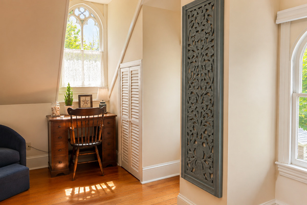 The other end of the same room — a writing desk, a reading chair, and a Gothic arch window that stops everyone who sees it. Plenty of space to spread out up here.