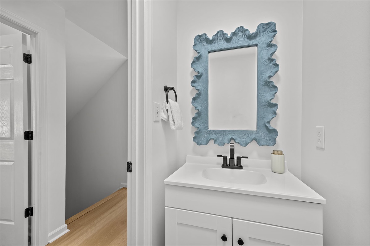 First floor powder room with modern vanity and coastal decor mirror

