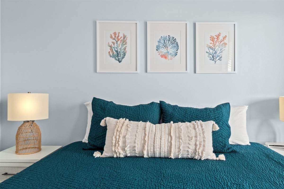 Sink into deep teal bedding under soft coastal art.