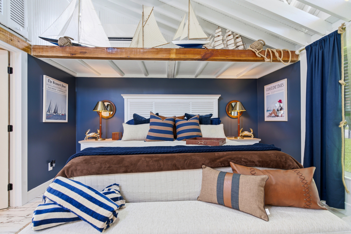 Welcome to the Sail room that features deep navy walls, vaulted ceilings, brass accents, and a fleet of vintage sailboat models overhead.