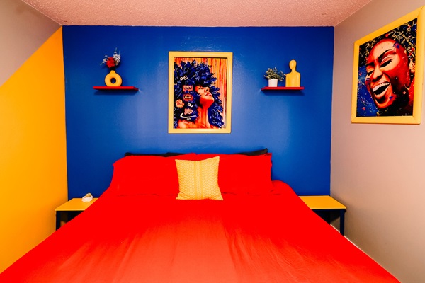 Royal Haven: Vibrant Red King-size Bed, Accented by a Dynamic Blue and Yellow Backdrop, Evoking Serenity and Style 🛏️💙🌟