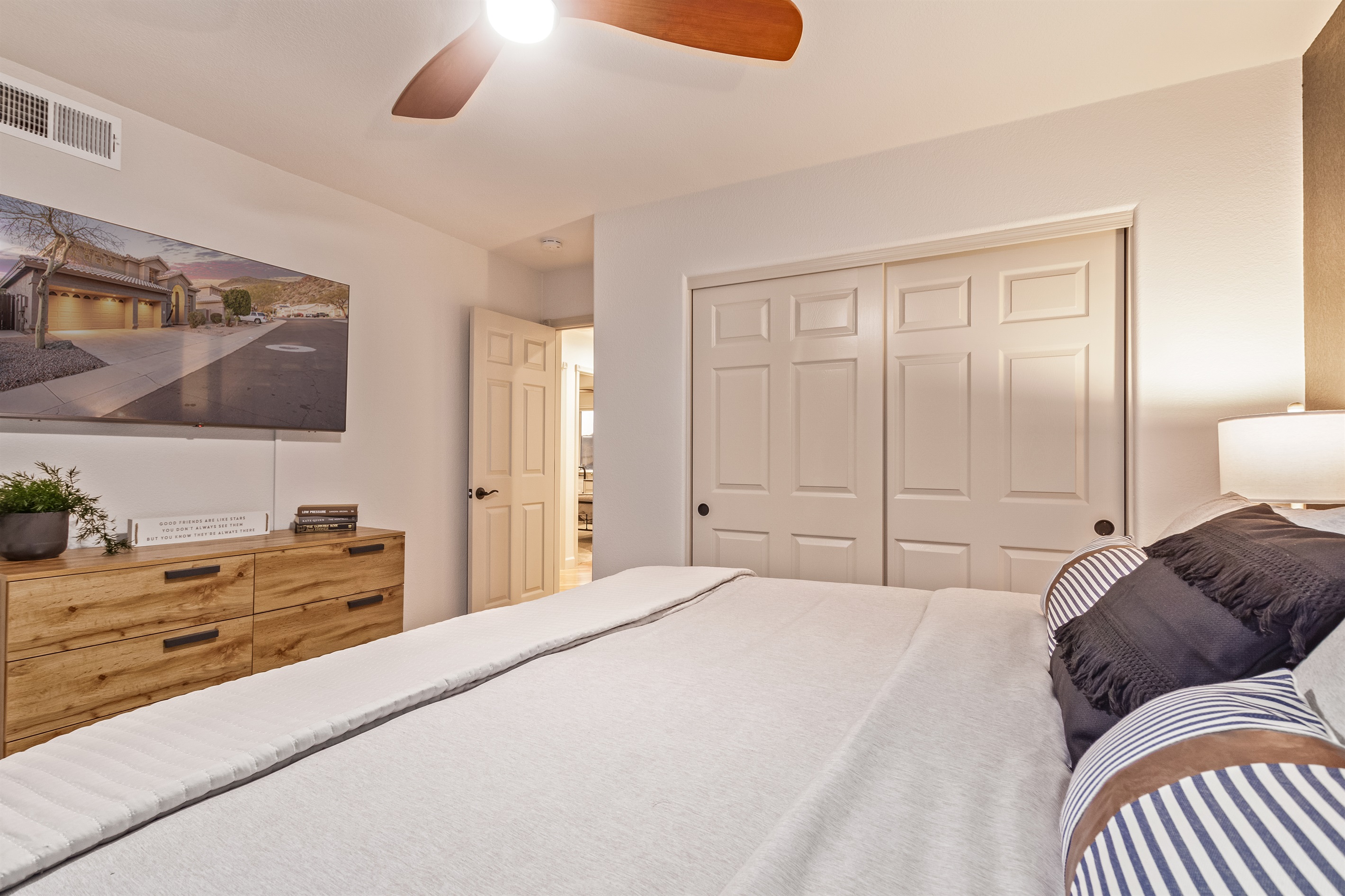 Fourth bedroom with king bed, 55" TV, ceiling fans, extra pillow and blankets, clothing storage, and room darkening shades 