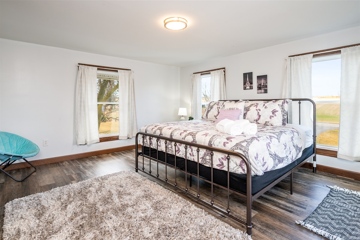 Cozy primary bedroom with a plush queen bed, natural light, and modern farmhouse decor—perfect for relaxing after a day exploring the Finger Lakes.