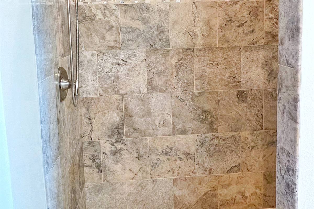 Step into a rainfall shower surrounded by natural stone finishes.