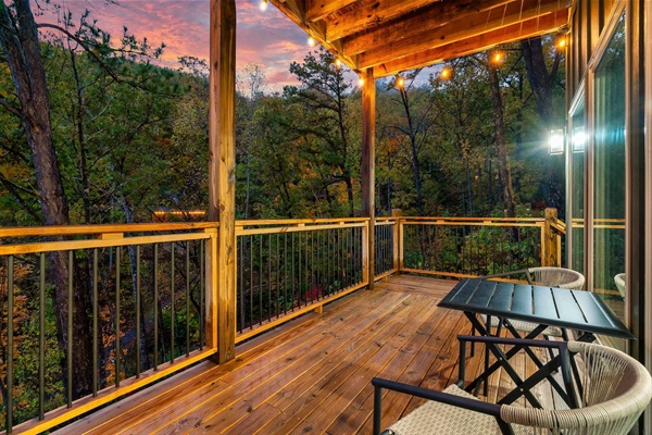 Lower-level private deck with string lights and peaceful wooded views.